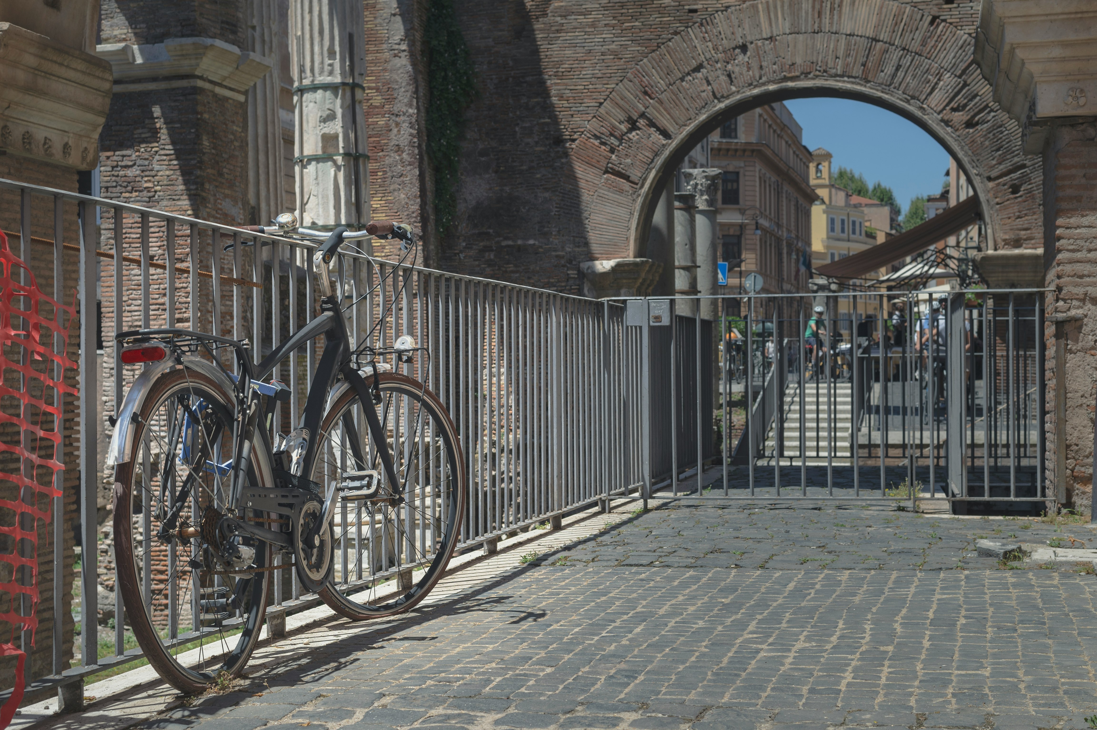 blue city bike parked beside gray metal fence during daytime